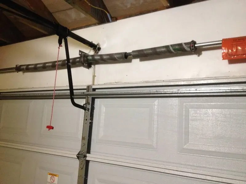 Broken torsion spring above a garage door, with a visible gap in the coil