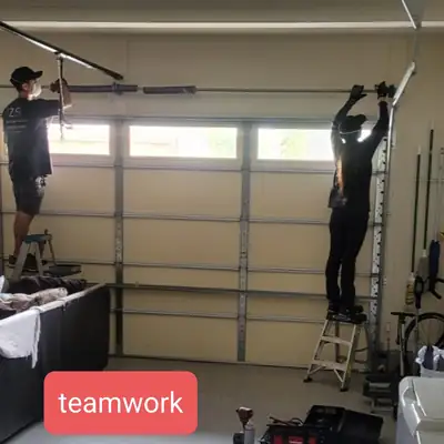 Two technicians working on a garage door